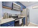 Stainless steel appliances and blue cabinets in galley-style kitchen at 4524 N Plantation Dr. # D9, Little River, SC 29566