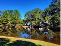 Waterfront view of homes and lush trees reflecting in calm water at 49 Daniel Morrall Ln., Georgetown, SC 29440