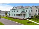 Two-story light green house with a front porch and landscaped yard in a neighborhood setting at 946 Crystal Water Way, Myrtle Beach, SC 29579