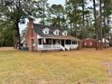 Inviting single-story brick home showcasing a quaint front porch, and a lush green lawn at 305 W Raft St., Nichols, SC 29581