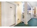 Front door entrance to condo, with white door and yellow siding at 4705 Wild Iris Dr. # 105, Myrtle Beach, SC 29577