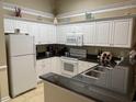 A well-equipped kitchen featuring white cabinets, black countertops, and modern appliances at 601 N Hillside Dr. # 4235, North Myrtle Beach, SC 29582