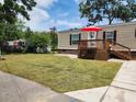 Tan mobile home with deck, red umbrella, and grassy yard at 818 Wayne St., North Myrtle Beach, SC 29582