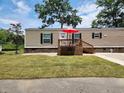 Tan mobile home with deck, red umbrella, and small yard at 818 Wayne St., North Myrtle Beach, SC 29582