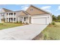 Two-car garage and covered porch. Tan and white exterior. Landscaped lawn at 7085 Shooting Star Way, Myrtle Beach, SC 29579