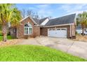 This is an inviting brick home with a two-car garage and well-maintained landscaping, set against a blue sky at 113 Preservation Dr., Myrtle Beach, SC 29572