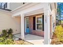 Charming covered front porch with white columns, brick accents, and a bright blue front door at 1303 Bermuda Grass Dr., Myrtle Beach, SC 29579