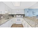 Well-lit kitchen featuring granite countertops, white cabinets, and stainless steel appliances at 5511 N Ocean Blvd. # 302, Myrtle Beach, SC 29577