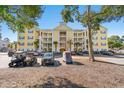 Building exterior showcasing a yellow facade, landscaping, and parking area at 601 Hillside Dr. N # 1506, North Myrtle Beach, SC 29582