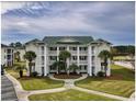 Condominium with balconies on each level, palm trees and walkway to entrance at 677 Tupelo Ln. # 301, Longs, SC 29568