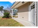 Inviting covered porch with vinyl siding and well-maintained lawn, showcasing the home's exterior at 413 Cotton Grass Dr., Loris, SC 29569