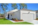 Newly built home featuring a white exterior, attached garage, and well-maintained lawn at 1357 Palm Springs Paloma Dr, Longs, SC 29568