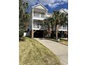 Charming raised beach house with covered parking and beautiful lawn with palm trees at 114-A 11Th Ave. S, Surfside Beach, SC 29575