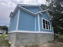 Side view of a blue home with white trim and a gray block foundation, highlighting its construction at 1004 James Island Ave., North Myrtle Beach, SC 29582