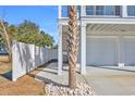 Side view of a light blue house with white garage, palm tree, and white fence at 434 Stanley Dr., Murrells Inlet, SC 29576