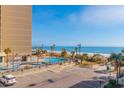 An elevated view of the condo complex pool, palm trees, beach access, and parking at 7200 N Ocean Blvd. # 314, Myrtle Beach, SC 29572