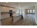 Modern kitchen featuring white cabinets, stainless steel appliances, an island, and hardwood floors in an open layout at 140 Joyce Dr, Longs, SC 29568