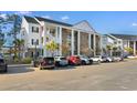 Condo complex with white pillars, brick facade, staircases and parking on a sunny day at 136 Birch N Coppice Dr. # 11, Surfside Beach, SC 29575