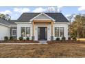 Modern farmhouse exterior features a gray-toned shingle roof, a dark gray front door, and a stylish wood beam accent at 270 Russ Rd., Loris, SC 29569