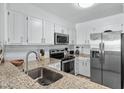 Well-lit kitchen featuring stainless steel appliances, granite countertops, white cabinets, and a stylish backsplash at 3701 S Ocean Blvd. S # 206, North Myrtle Beach, SC 29582