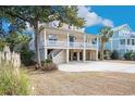 Stilt home boasting a large porch and a low-maintenance yard with mature trees at 438 Cayman Loop, Pawleys Island, SC 29585