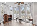 Bright sun room with a ceiling fan, fireplace, and multiple windows with white curtains at 4396 Baldwin Ave. # 94, Little River, SC 29566
