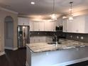 Modern kitchen featuring white cabinetry, stainless steel appliances, granite countertops, and stylish pendant lighting at 600 Barona Dr., Myrtle Beach, SC 29579