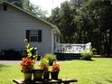 View of backyard, with a well-manicured lawn, flowers, and a glimpse of the outdoor living area at 76 Nailah Ln., Pawleys Island, SC 29585