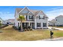 Charming two-story home with gray siding, black shutters, a palm tree, and a well-manicured lawn at 931 Desert Wheatgrass Dr., Myrtle Beach, SC 29579