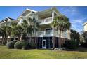 Side view of tan condo building with a screened in porch and palm trees at 1004 Ray Costin Way # 206, Murrells Inlet, SC 29576