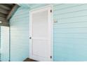 Close-up of an exterior door with white louvers on a light blue building with a door mat at 1510 S Ocean Blvd. # 101, Surfside Beach, SC 29575