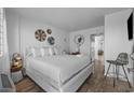 Bright bedroom featuring a bed with white linens, decor wall hangings, and wicker chair at 2001 S Ocean Blvd. # 1405, Myrtle Beach, SC 29577