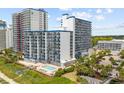 Low aerial view of a beachfront white condominium complex with blue accents and a pool at 2001 S Ocean Blvd. # 1405, Myrtle Beach, SC 29577