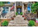 Grand brick stairs with potted flowers leads to the front door, adorned with a decorative wreath and the American flag at 2803 Ships Wheel Dr., North Myrtle Beach, SC 29582