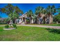 Beautiful brick home featuring mature palm trees, a circular driveway, and a charming crane statue in a lovely landscaped yard at 2803 Ships Wheel Dr., North Myrtle Beach, SC 29582