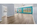 Open-concept living space with a vibrant accent wall, wood flooring, and large windows for natural light at 5215 Southern Trail, Myrtle Beach, SC 29579