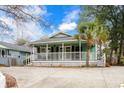 Charming green home featuring a welcoming wraparound porch, inviting relaxation and enjoyment at 5520 N Kings Hwy., Myrtle Beach, SC 29577