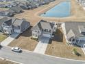 Aerial view of a charming gray two-story home with a double porch and community pond nearby at 1047 Harbison Circle, Myrtle Beach, SC 29579