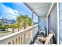 Balcony view of the street with chairs and a white railing with palm trees at 1210 N Ocean Blvd. # 202, Surfside Beach, SC 29575