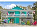 Two-story home with colorful siding, white railings and colorful chairs at 402 13Th Ave. S, North Myrtle Beach, SC 29582