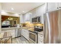 Modern kitchen featuring white cabinets, stainless steel appliances, granite countertops, and an open view to the living area at 5507 N Ocean Blvd. # 304, Myrtle Beach, SC 29577