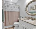 Well-lit bathroom with granite vanity, decorative mirror, and stylish shower curtain at 8217 Sandlapper Way, Myrtle Beach, SC 29572