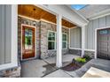 Inviting front porch featuring brick accents, white columns, and a wooden front door with glass panels at 1007 Brood Ct., Conway, SC 29526