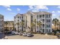 A full exterior of the building, featuring multiple floors, staircases, and a parking area with several cars at 117 Ella Kinley Circle # 302, Myrtle Beach, SC 29588