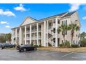 Condo building with white columns, balconies, green shutters, and ample parking under a cloudy sky at 5070 Windsor Green Way # 204, Myrtle Beach, SC 29579