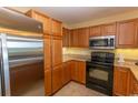 Modern kitchen with stainless steel refrigerator and microwave with black oven and brown cabinetry at 8121 Amalfi Pl. # 4-702, Myrtle Beach, SC 29572