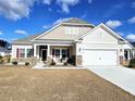 Traditional home with a well-maintained lawn, two-car garage, stone and shaker accents and inviting front porch seating at 925 Oak Hollow St., Longs, SC 29568