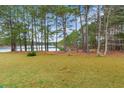 Spacious backyard with view of the serene lake, tall trees, and lush green grass at 158 Shady Arbor Loop, Longs, SC 29568