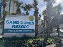 Sand Dunes Resort sign surrounded by palm trees and colorful landscaping at 201 N 74Th Ave. N # 2322, Myrtle Beach, SC 29572