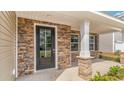 Covered front porch with stone pillars, side window, and modern black front door at 7006 Shooting Star Way, Myrtle Beach, SC 29579